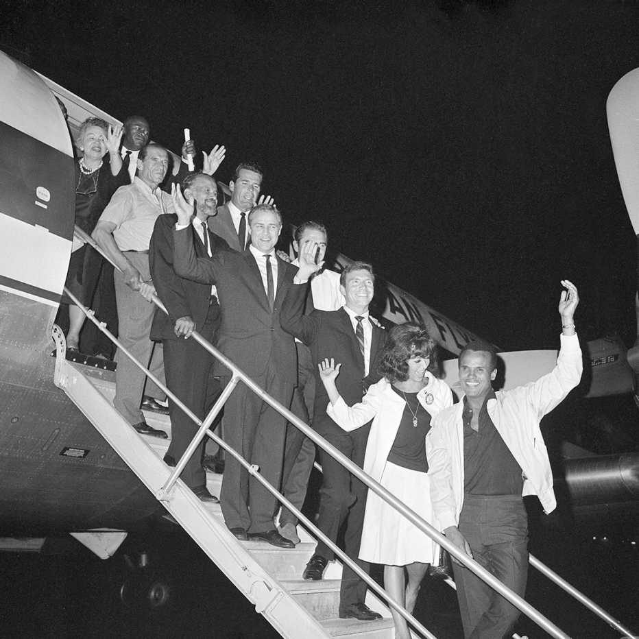 hollywood celebrities pose on the steps before boarding an airplane for the march on washington in nineteen sixty three actors frank silvera james garner marlon brando steve cochran anthony franciosa rita moreno and harry belafonte