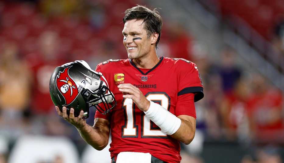 Tom Brady smiling on the field holding his Tampa Bay Buccaneers helmet prior to the game against the Baltimore Ravens at Raymond James Stadium in Tampa, Florida.