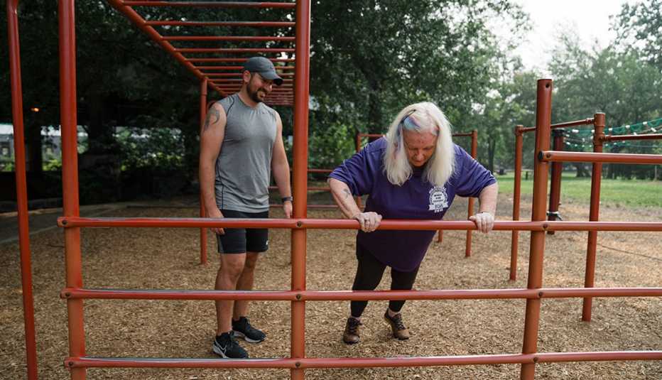 susan kelly does modified pushups on playground equipment under the instruction  of her personal trainer mike tandoori