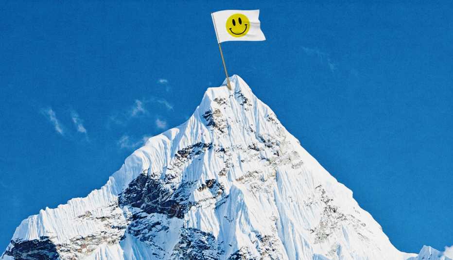a white flag with a smiley face on it atop a white mountain against a blue sky