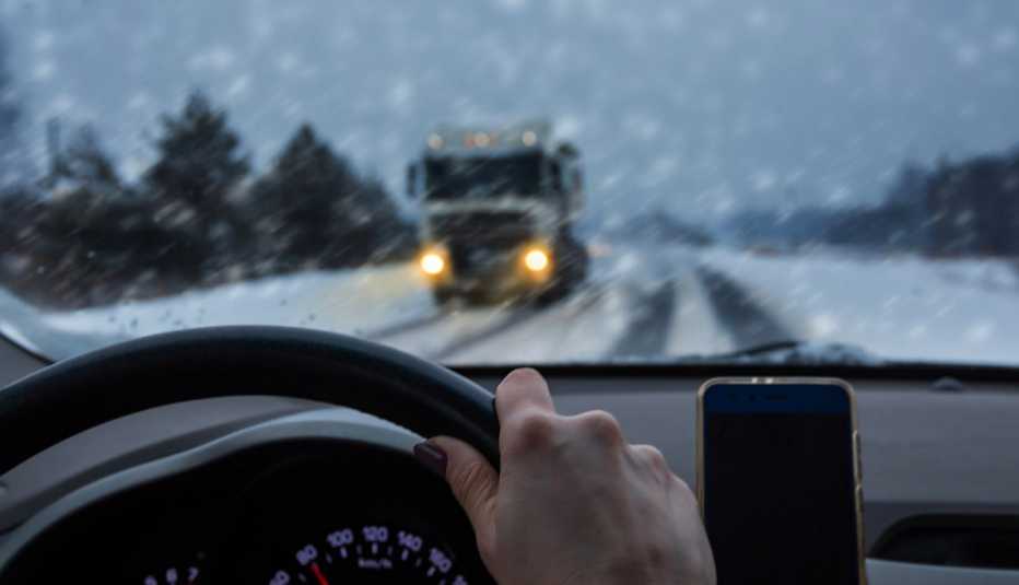 a woman driving on a snowy road with a truck oncoming