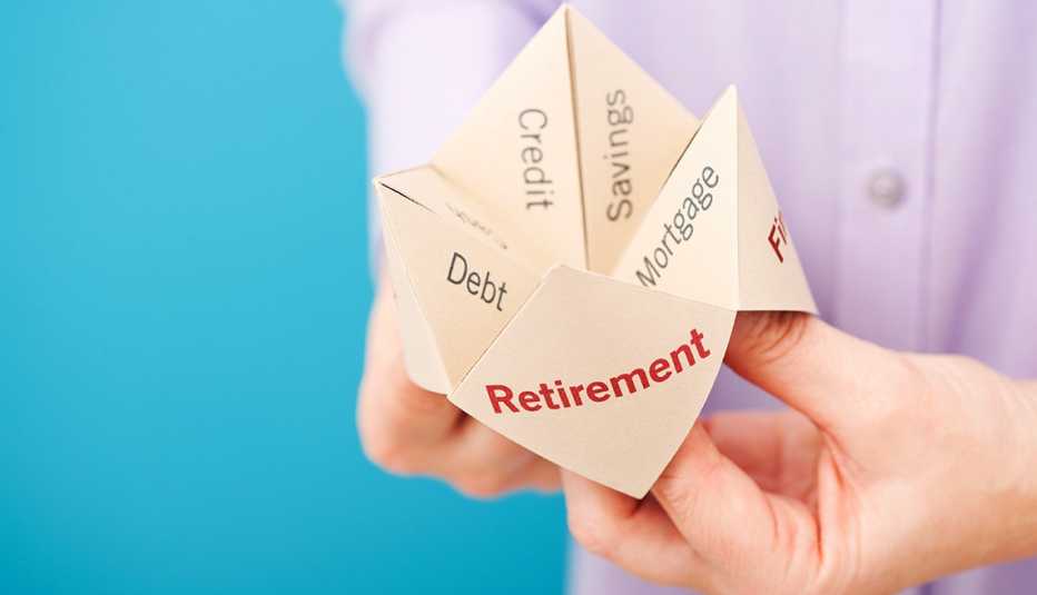 A closeup of someone using a folded paper fortune teller game that is marked with indicators related to retirement finances.