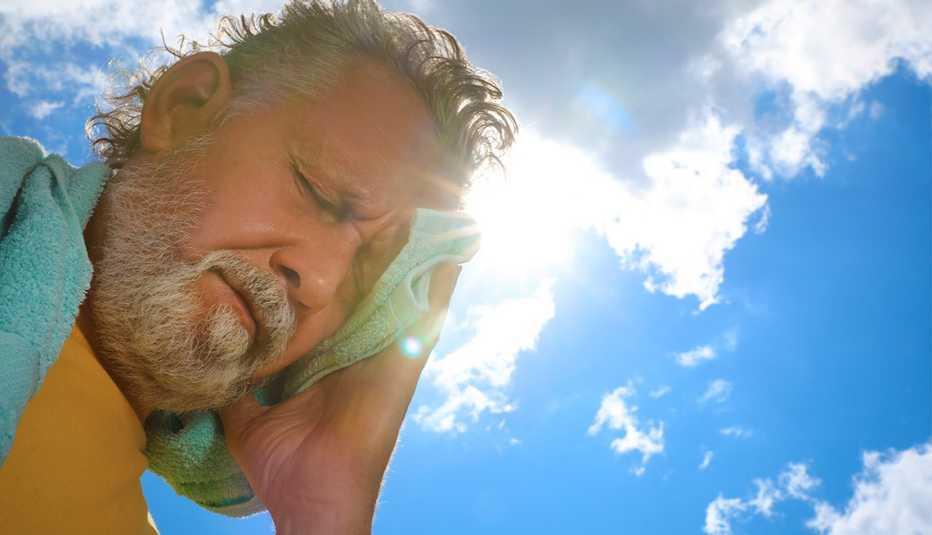 man with towel suffering from heat stroke outdoors in the sun, low angle view. 