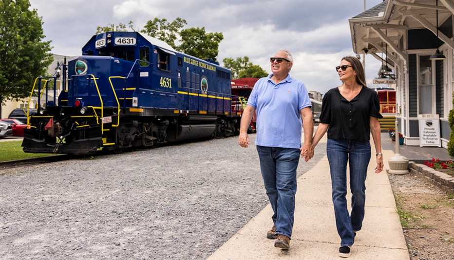 mark and tracy esquenazi walking at a train station of the blue ridge railway