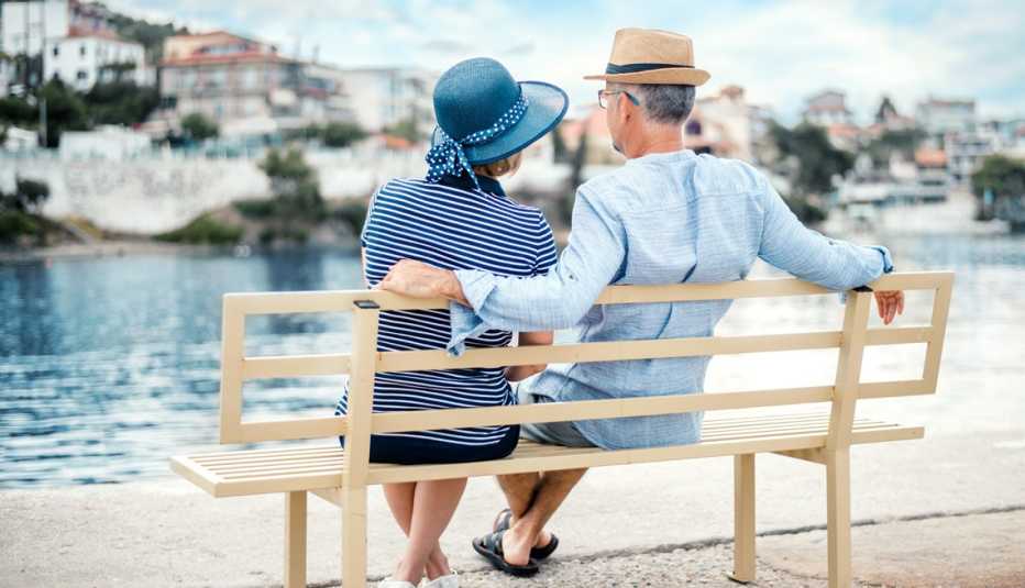 a romantic couple sitting on a bench in front of the mediterranean in greece