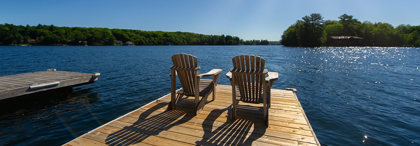 two adirondack chairs on a lake dock