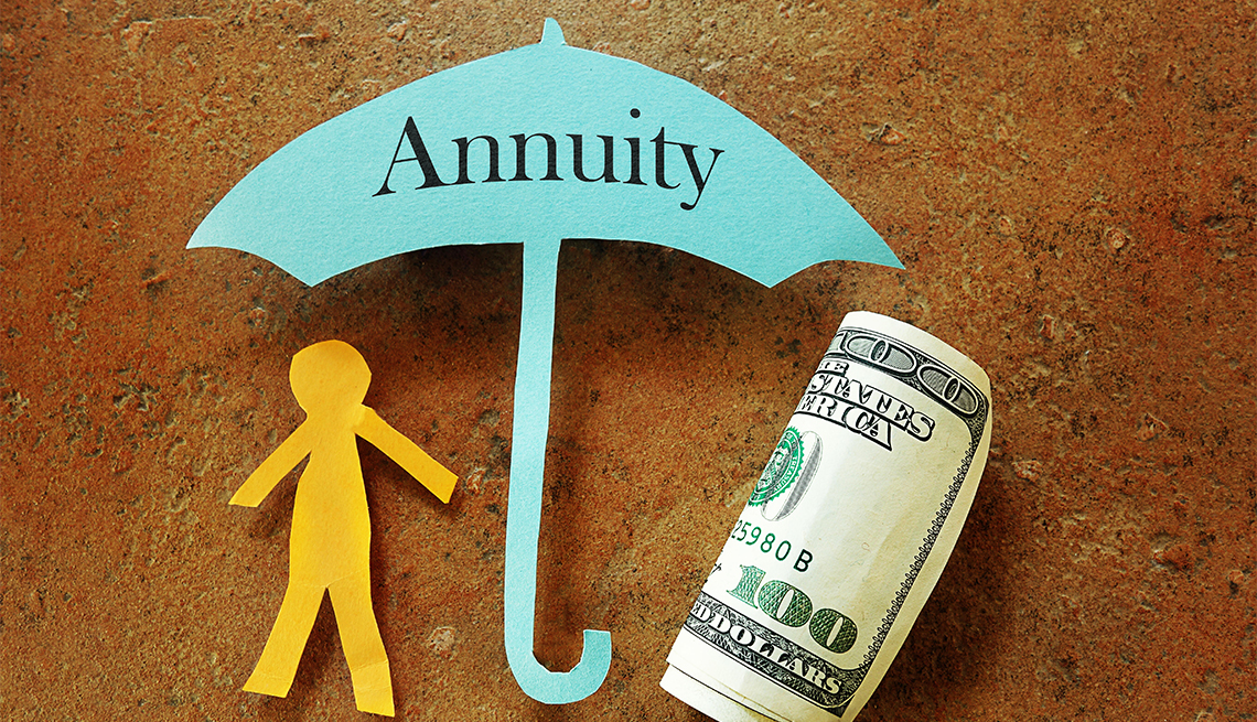 paper cut out stick figure and a rolled up hundred dollar bill sheltered under a paper cut umbrella labeled annuity