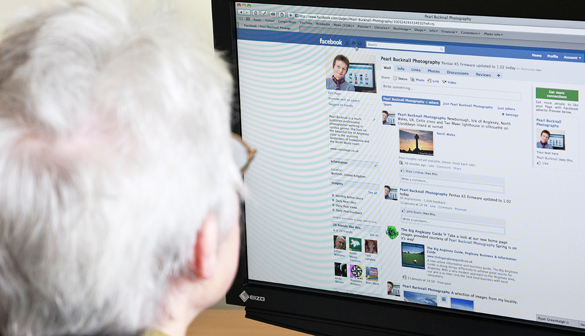 Senior woman using Internet to look at this photographers business page on Facebook social media website webpage on a home computer.