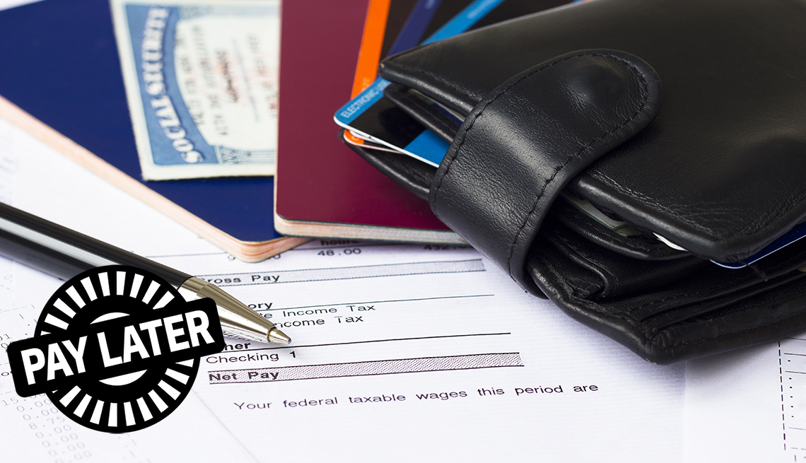 pay later stamp on top of paycheck, pay statements, wallet, passports, credit cards and social security card