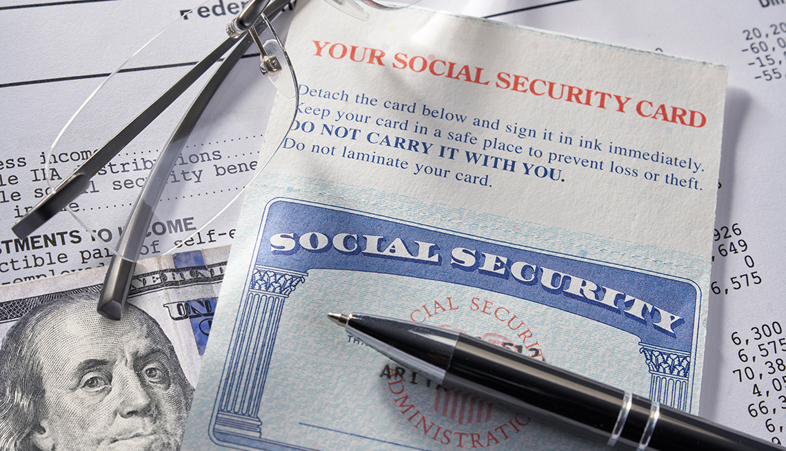 closeup display of Social Security card with money, pen, eyeglasses, $100 dollars