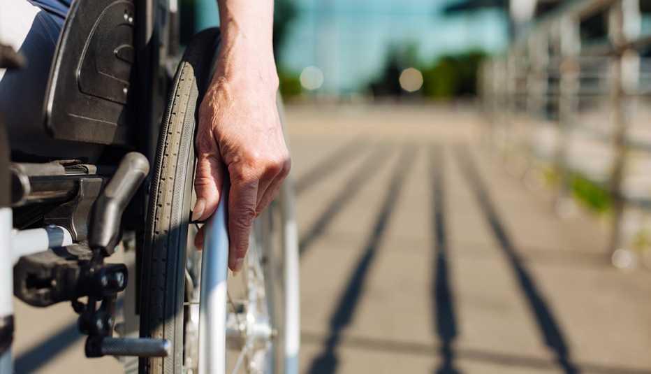 closeup of a persons hands on the wheel of their wheelchair outdoors 