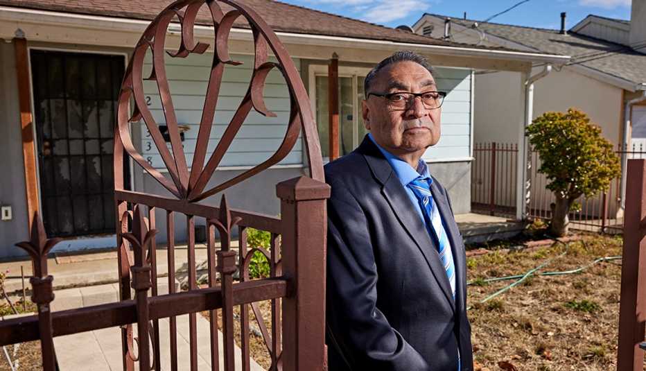 jose stands just inside the open fence gate in his front yard