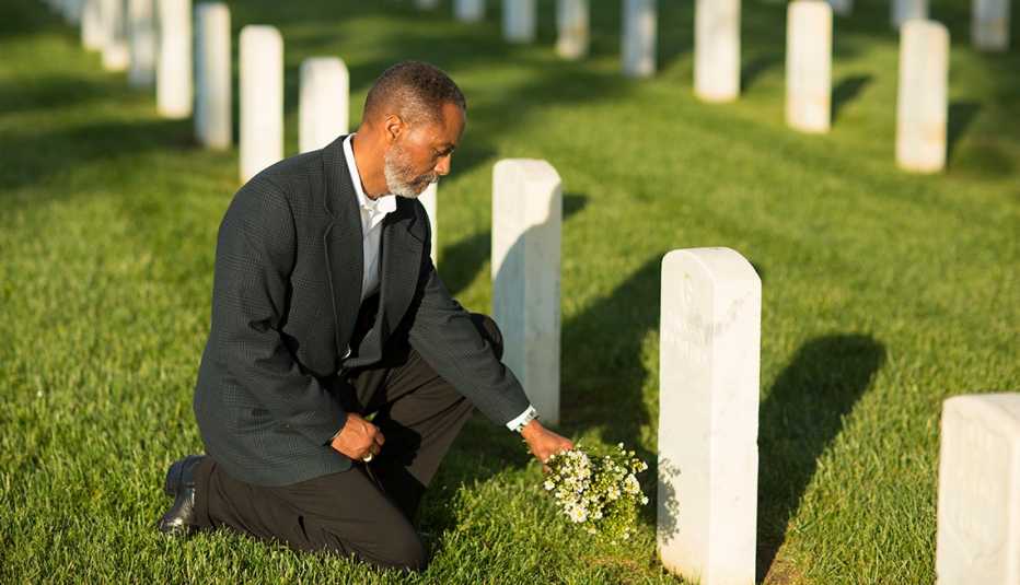 widower kneeling at gravesite
