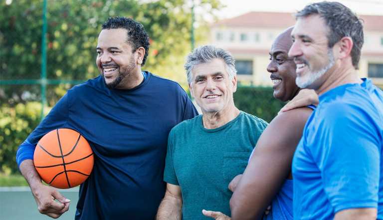 A multi-ethnic group of middle-aged and senior men on an outdoor basketball court
