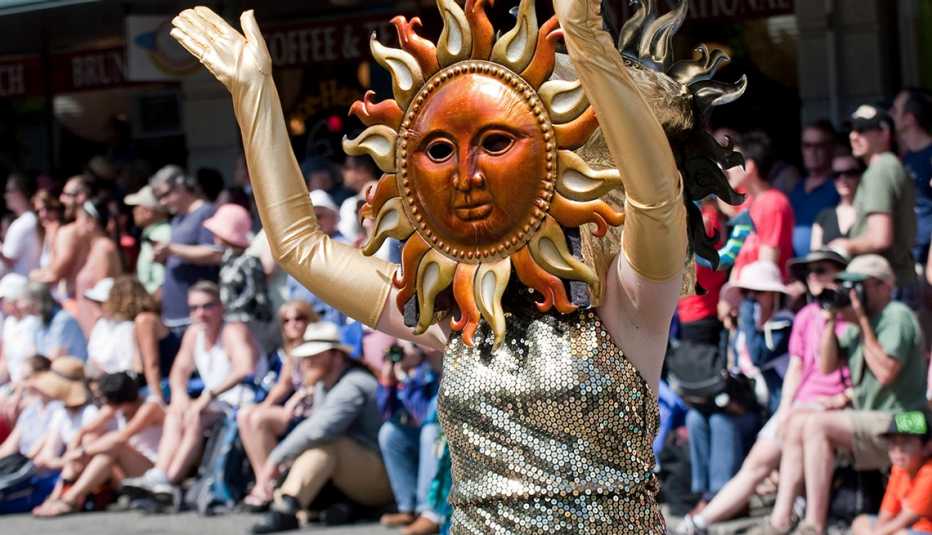 A woman wearing golden dress and sun mask on a street during Fremont Solstice Parade in Seattle, WA 
