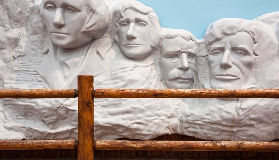 a mount rushmore model behind a wooden fence at wall drug in south dakota