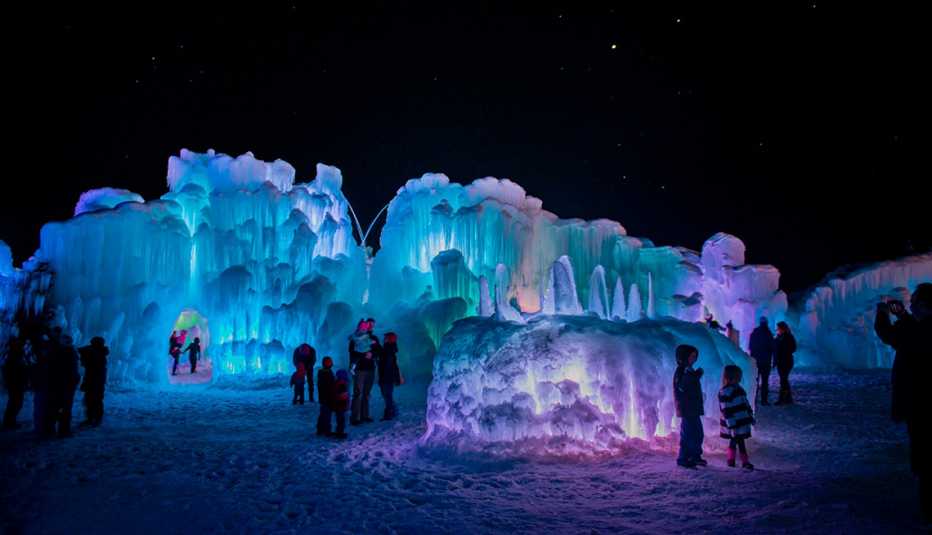 ice castles lit up with bright colors at night as people tour them