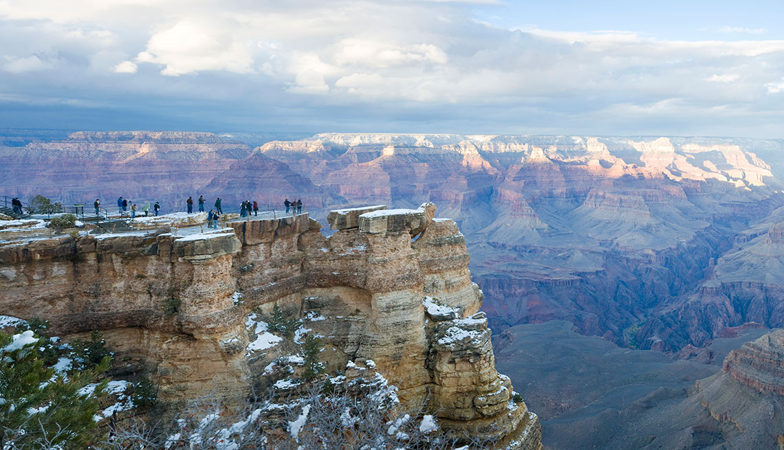 people standing on a snowy outcropping above the grand canyon in arizona