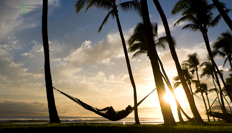 a person in a hammock at sunset on kaanapali beach in maui hawaii