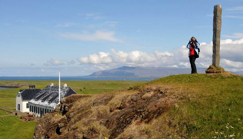 woman on a hill taking photos on Videy Island, Iceland