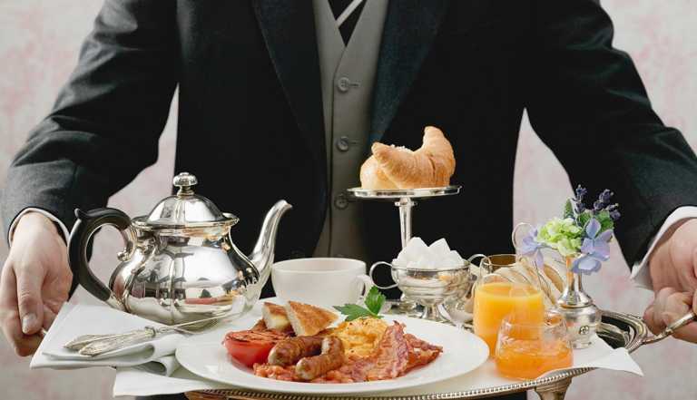 a butler holding a tray of breakfast for guests