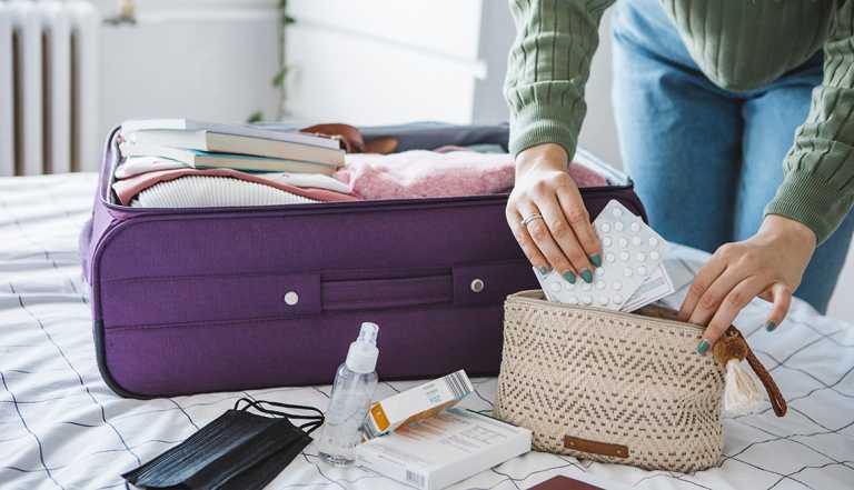 a woman is packing her suitcase and putting her medicine in her carry on bag