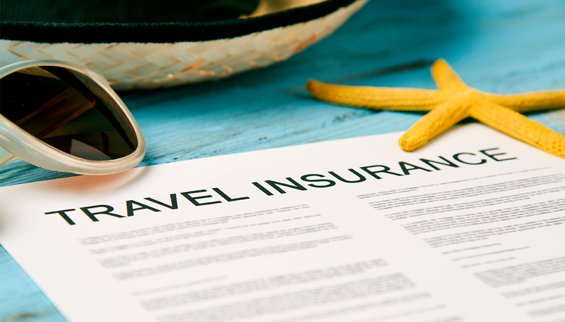 paperwork for travel insurance next to a starfish a straw hat and sunglasses
