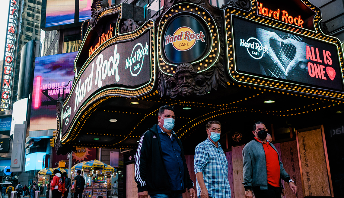 Pedestrians wearing protective mask pass in front of the Hard Rock Cafe in the Times Square neighborhood of New York