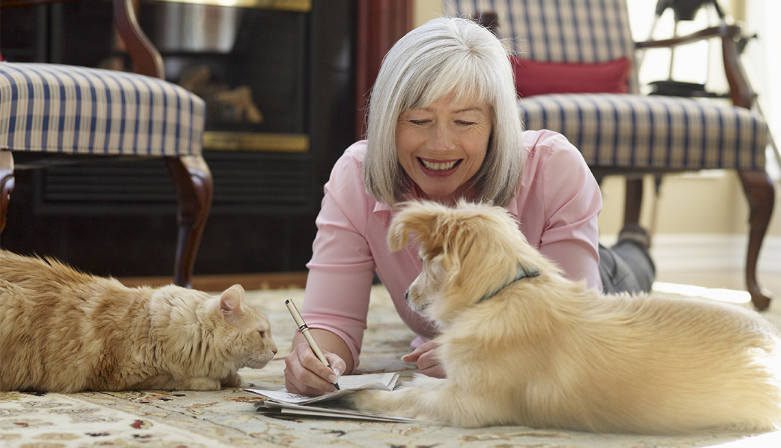 woman smiling at dog and cat laying on the floor