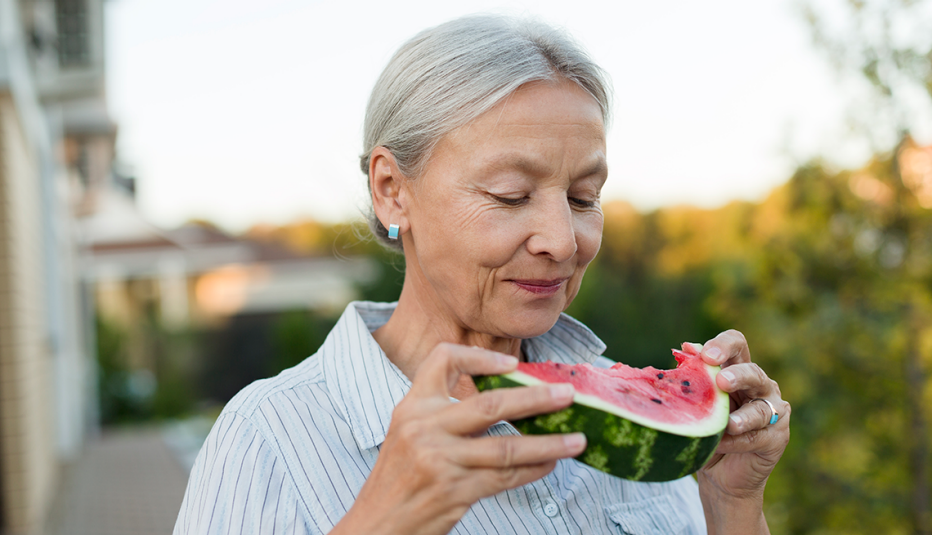 a woman eating a slice of watermelon to replenish electrolytes