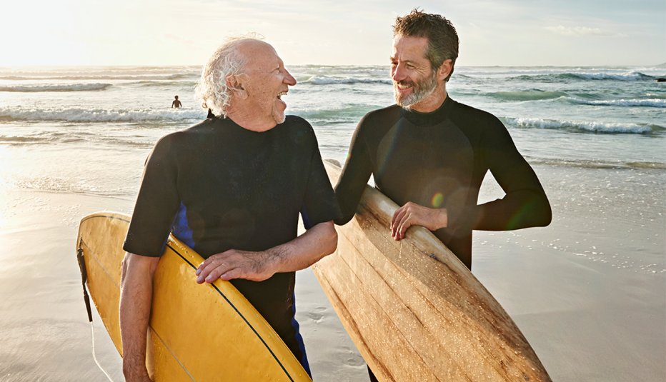 a father and son on a beach holding surfboards