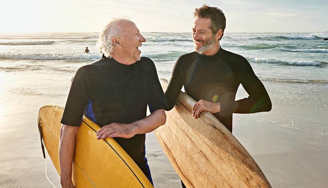 a father and son on a beach holding surfboards