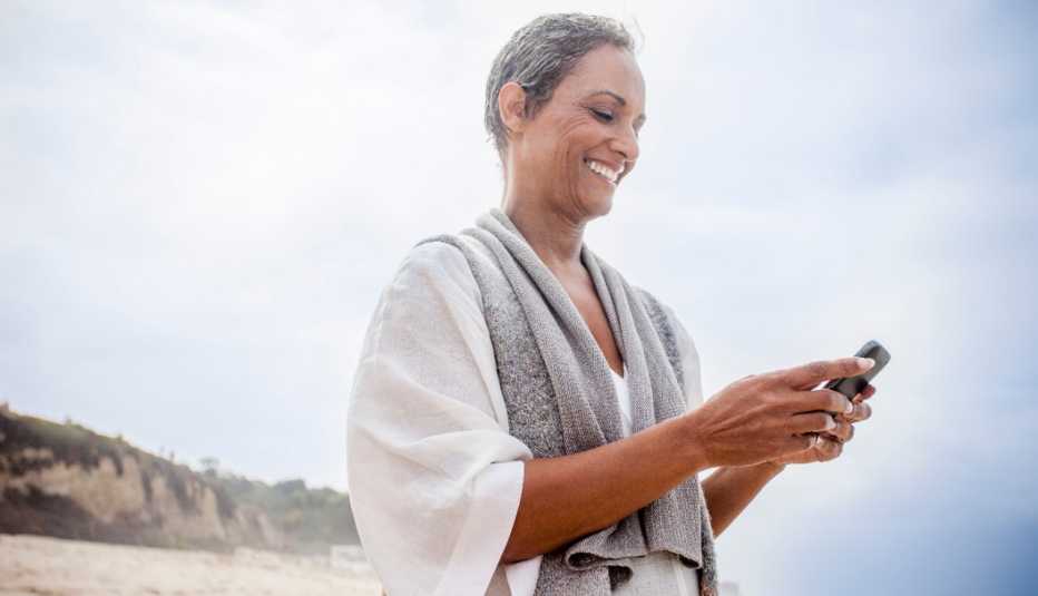 woman checks her phone on the beach