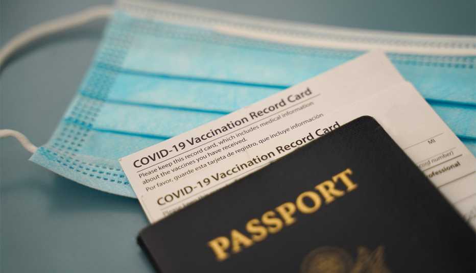 covid vaccine card, US passport and a mask on a gray background