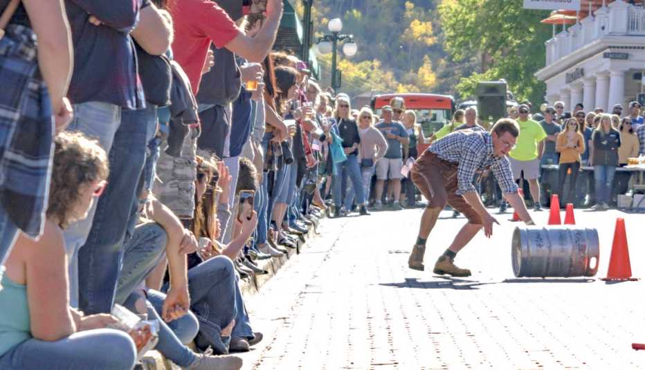 a man rolls a barrel in front of a cheering crowd during a fall festival event