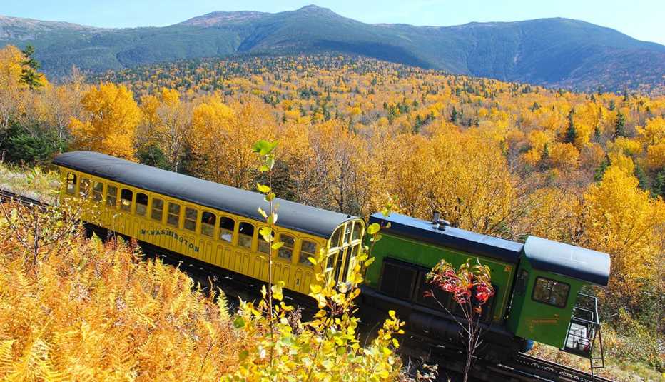 a biodiesel locomotive driving through a yellow autumn forest on the mount washington cog railway