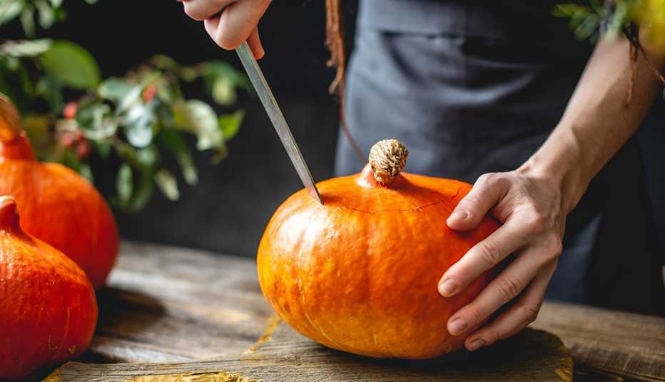 a chef's hands carving a pumpkin to prepare food