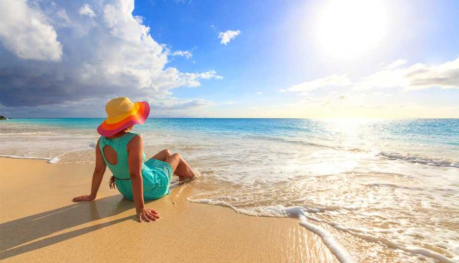 Woman with hat sit on seashore in Antigua
