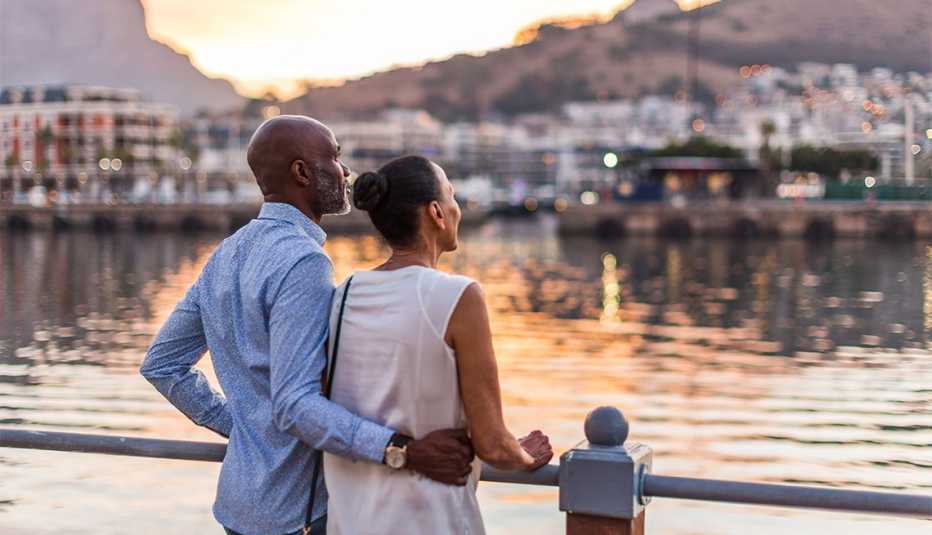 couple at waterfront gazing at city during sunset