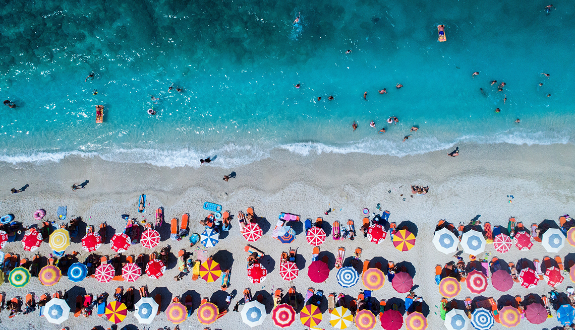 rows of beach umbrellas at the ocean as seen from overhead 