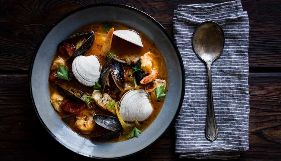 a bowl of cioppino with a spoon on a napkin