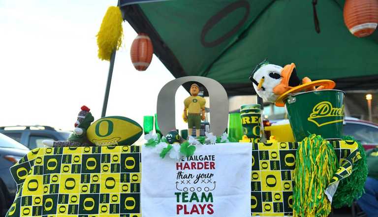 View of table at tailgate with towel that reads 'We tailgate harder than your team plays' outside Autzen Stadium 
