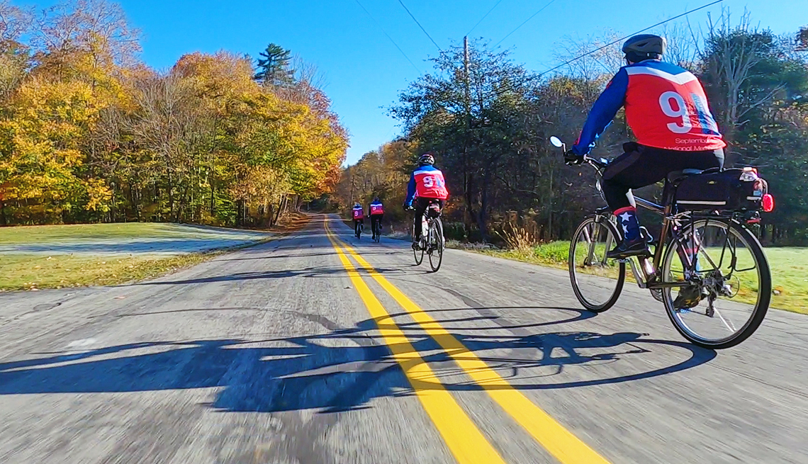 four people on bicycles wearing jerseys commemorating 9 11 riding on a country road