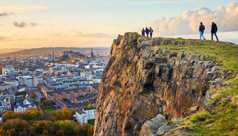 people on a cliff overlooking edinburgh scotland