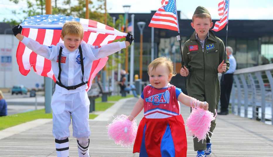 a little girl and two young boys carry american flags and other items during a july 4 celebration in ireland