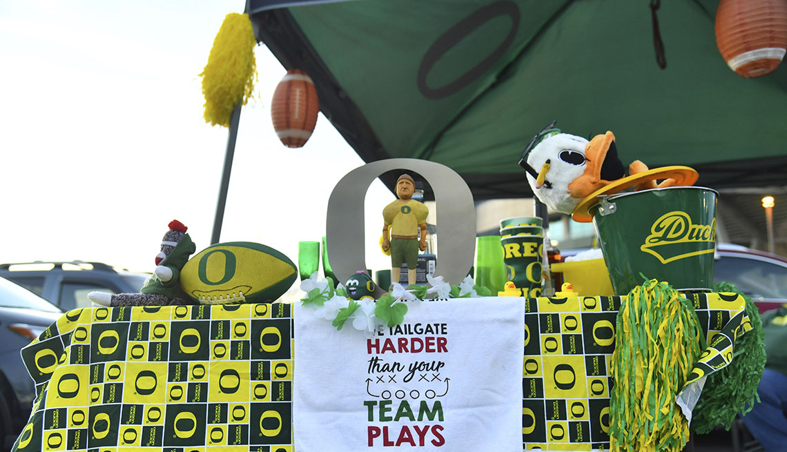 View of table at tailgate with towel that reads 'We tailgate harder than your team plays' outside Autzen Stadium 