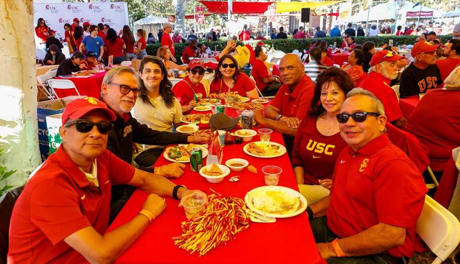 a group of USC alumni sit at a table to enjoy a food before a USC football game