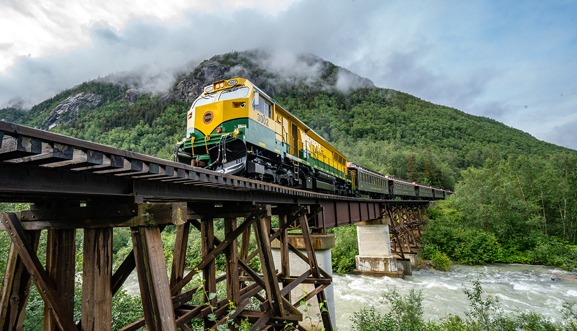 the white pass and yukon trail train crossing a bridge over rough river water
