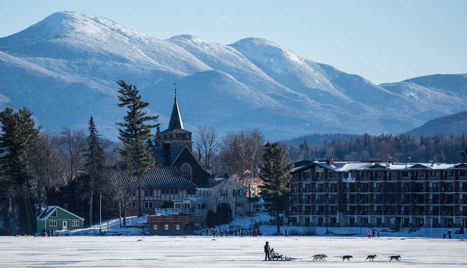a group of sledge dogs pulls a sleight across frozen lake placid under a bright sky
