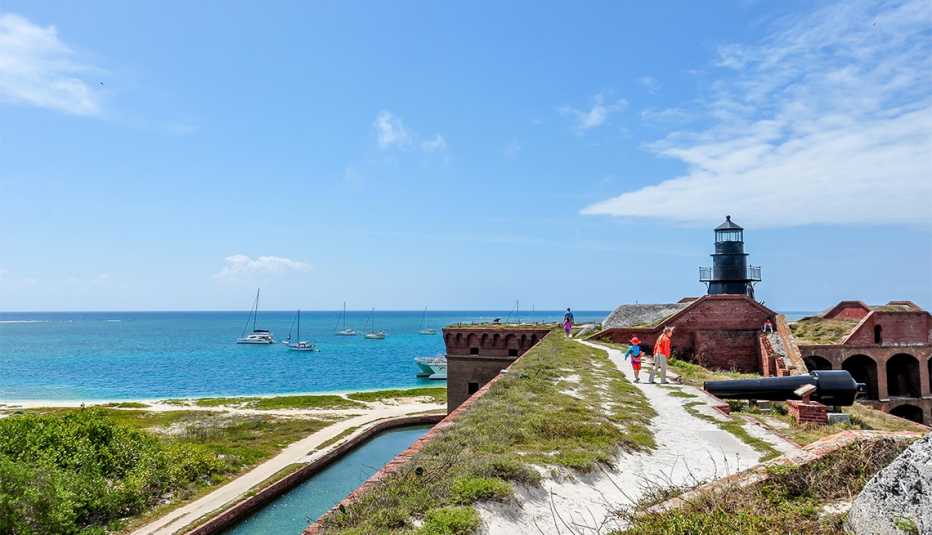 Kids explore Fort Jefferson at Dry Tortugas National Park with their father, walking along the roof with view of lighthouse, water and sailboats